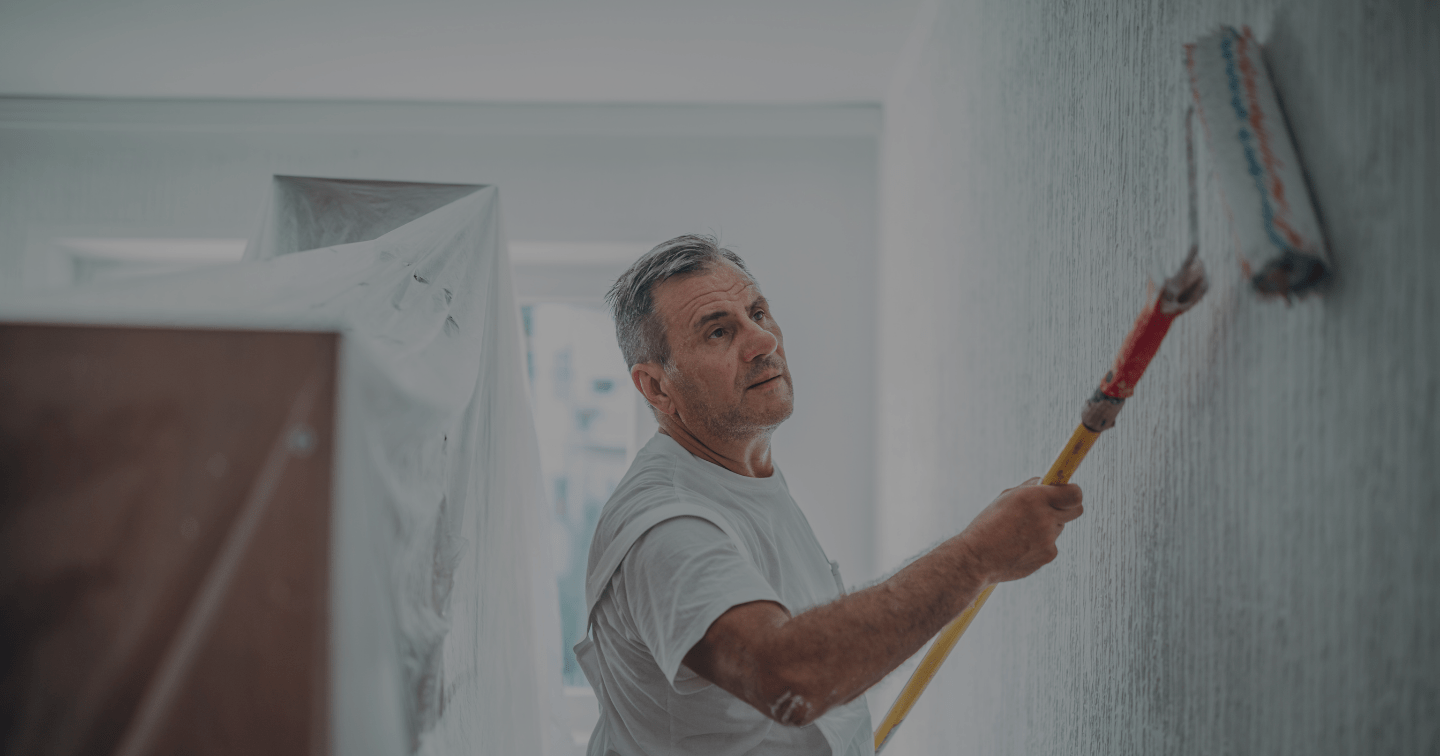 photo of a painter and decorator rolling paint onto an interior wall